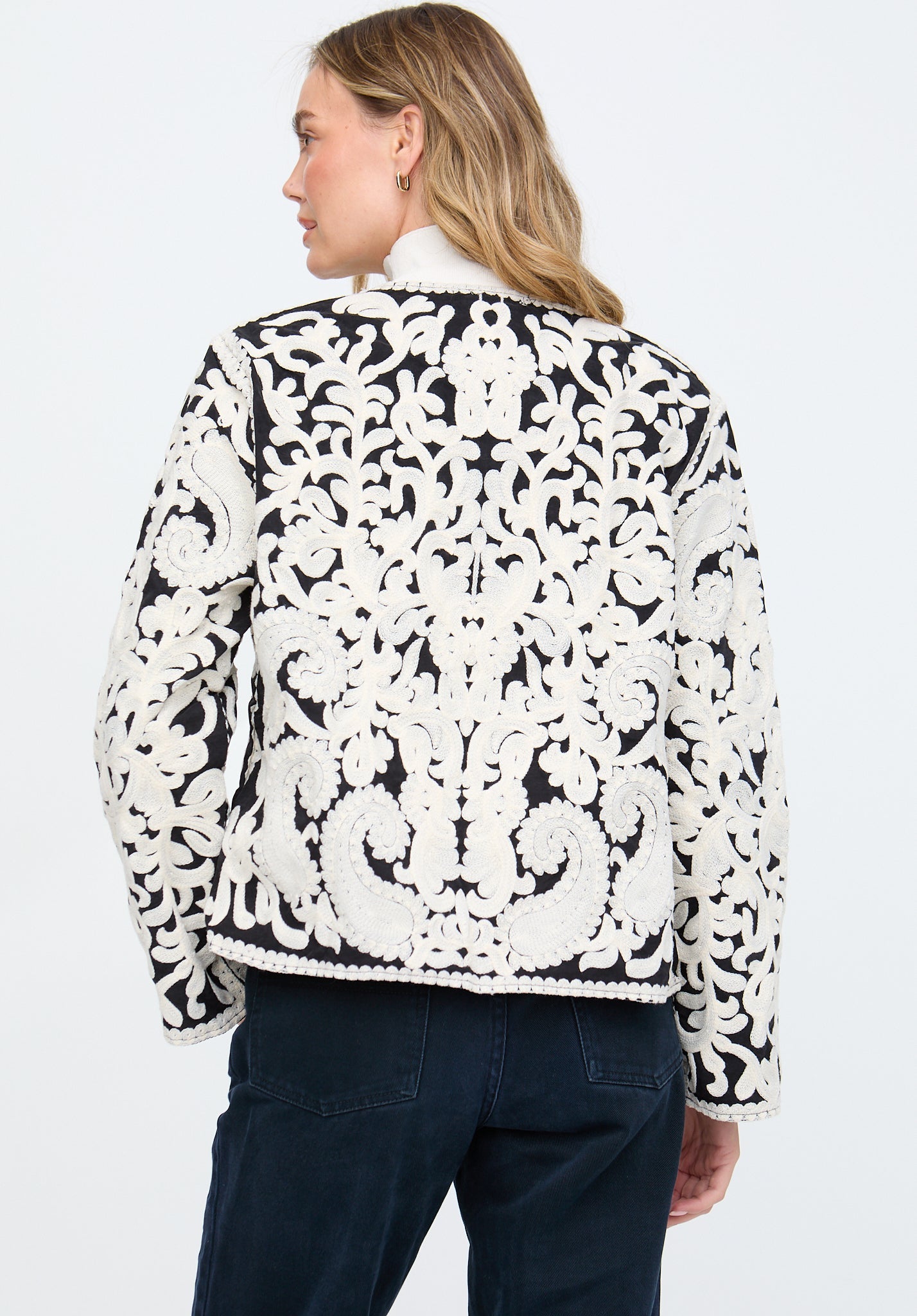 Woman wearing a black and white patterned jacket on a plain background