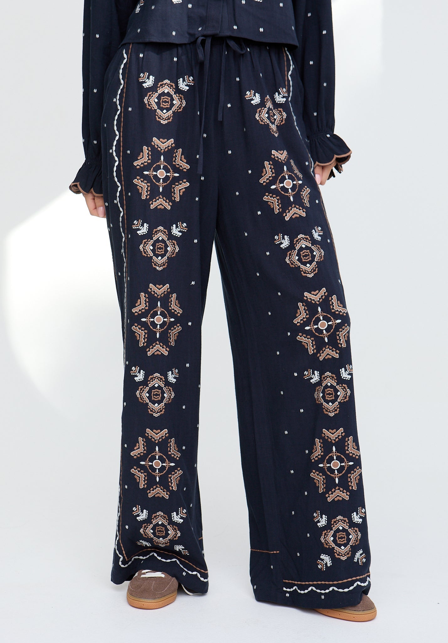 Navy blue pants with gold embroidery on a white background