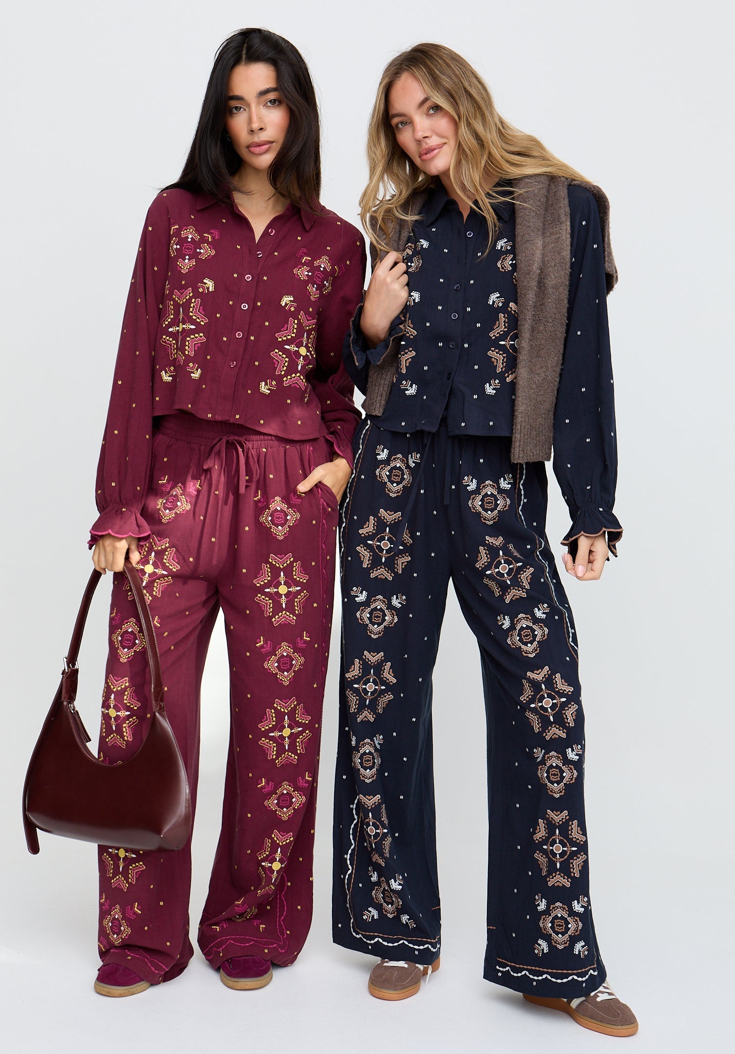 Two women wearing matching outfits with floral patterns on a white background
