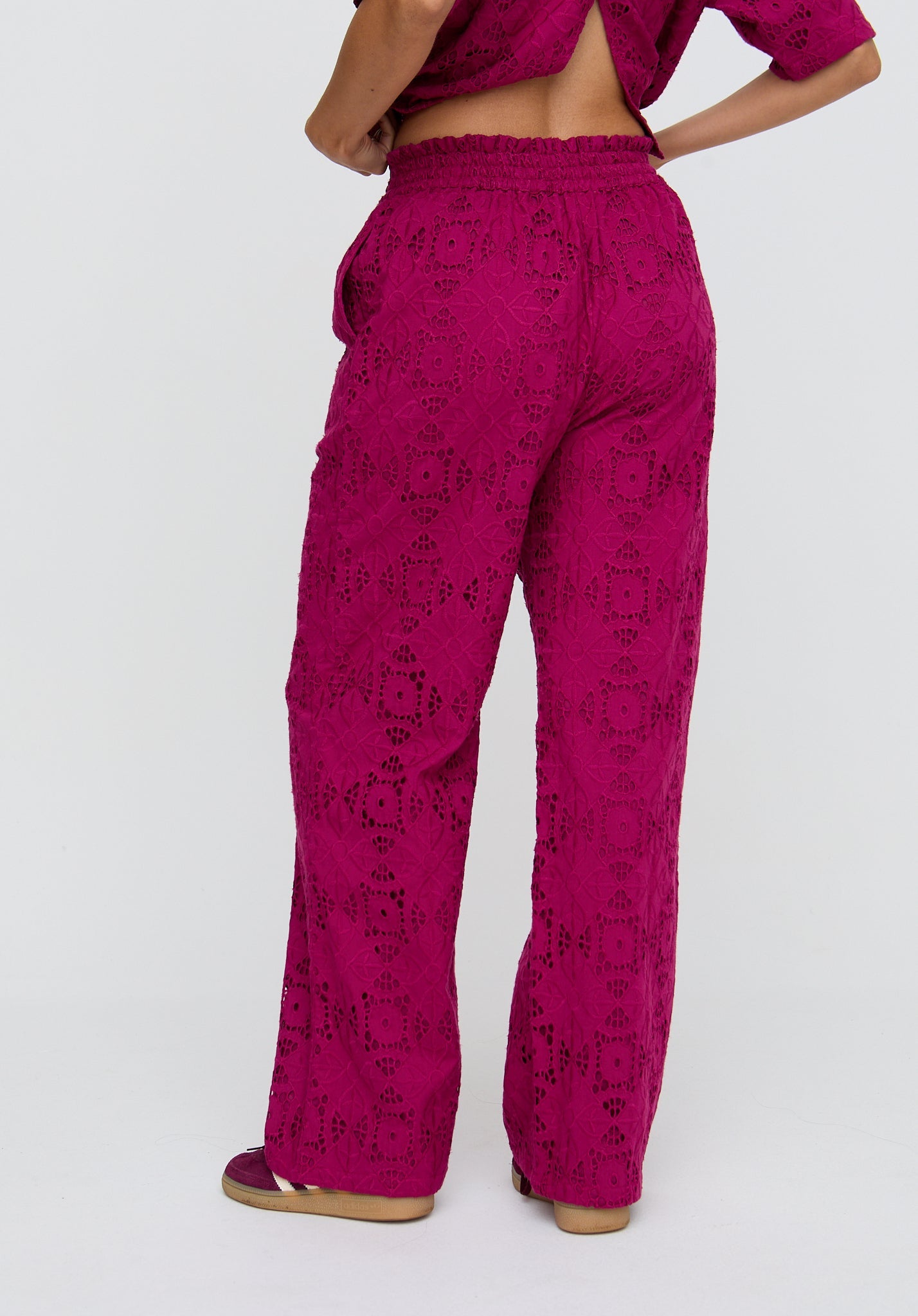 Person wearing magenta patterned pants on a white background