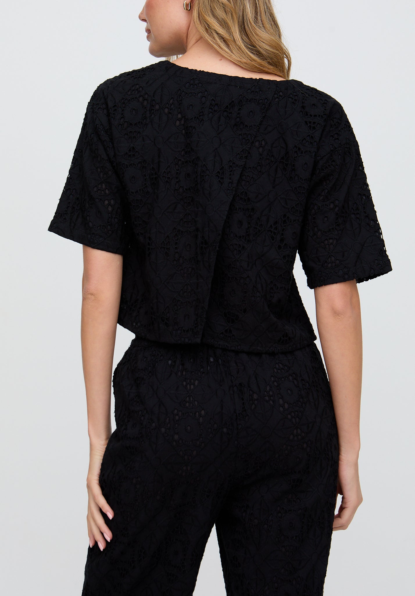 Person wearing a black textured outfit on a plain background