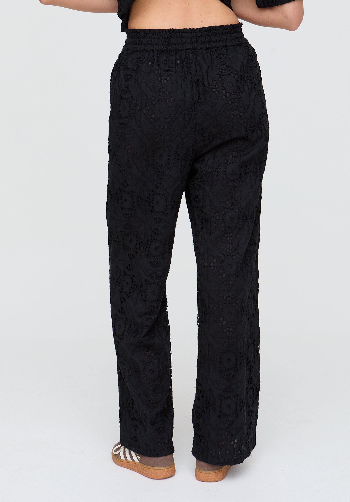 Black textured pants worn by a person on a white background