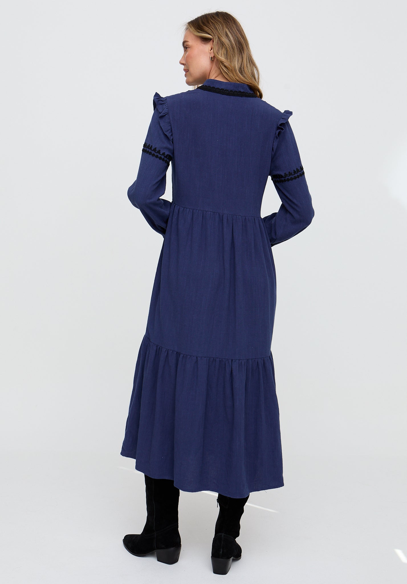 Woman wearing a blue dress with ruffled details on a white background