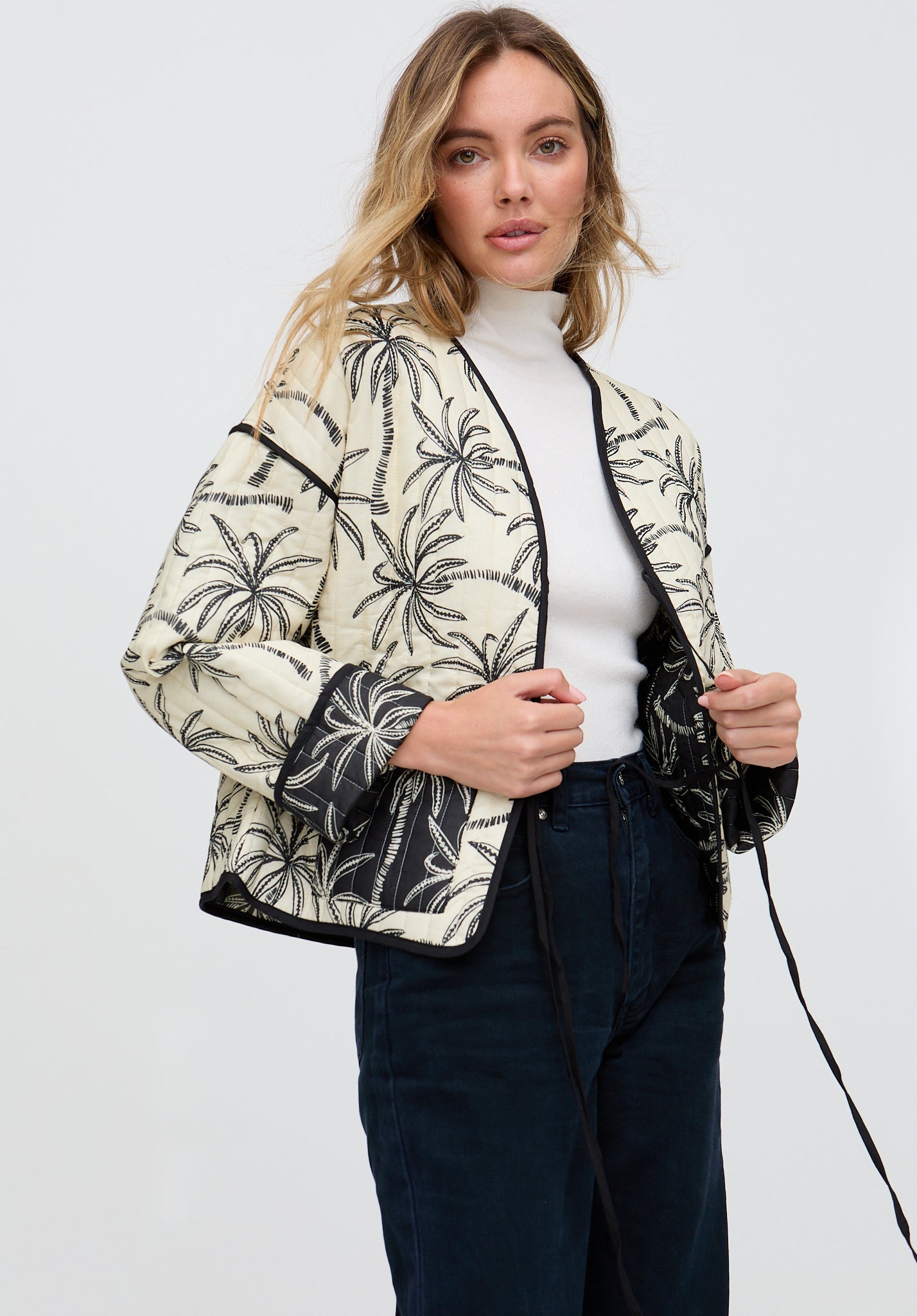 Woman wearing a patterned jacket over a white shirt on a plain background