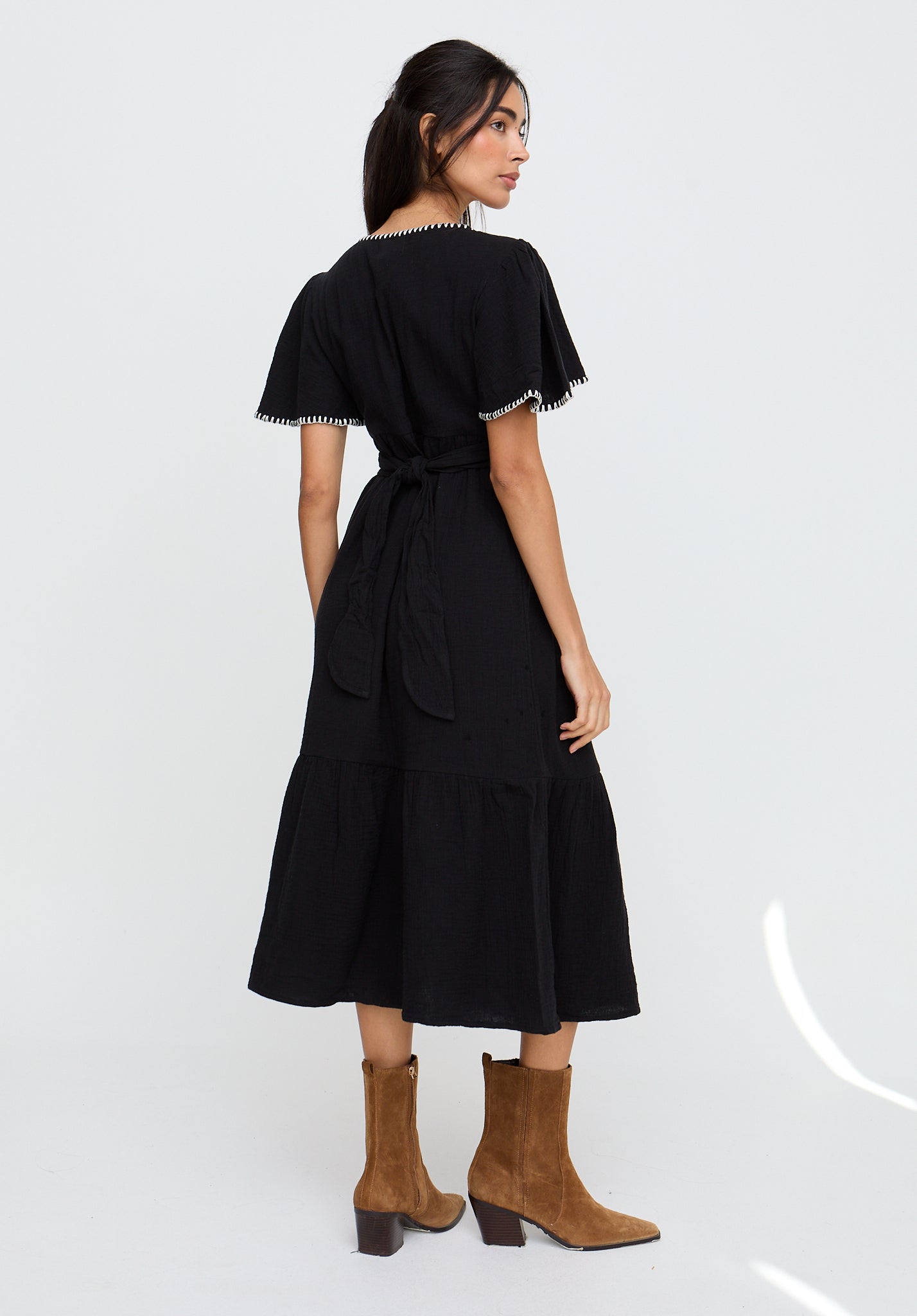 Woman wearing a black dress with sheer sleeves on a white background