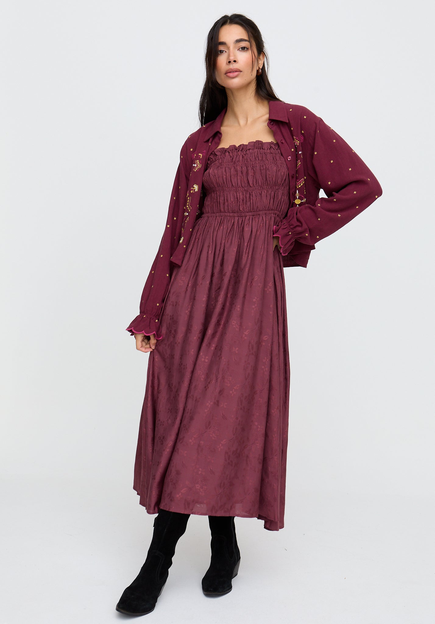 Woman wearing a burgundy dress with a matching jacket on a white background