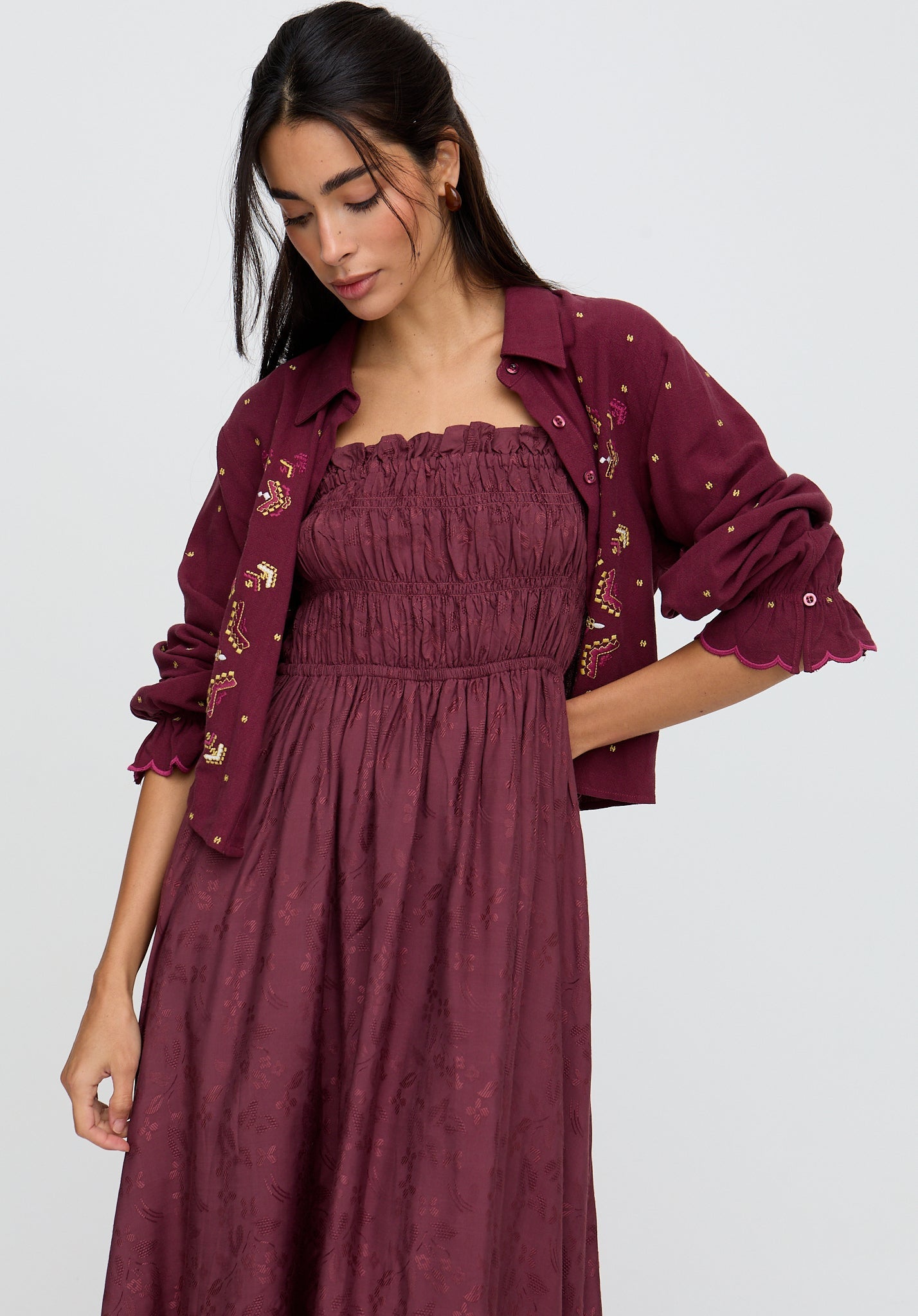 Woman wearing a burgundy dress with a matching jacket on a white background