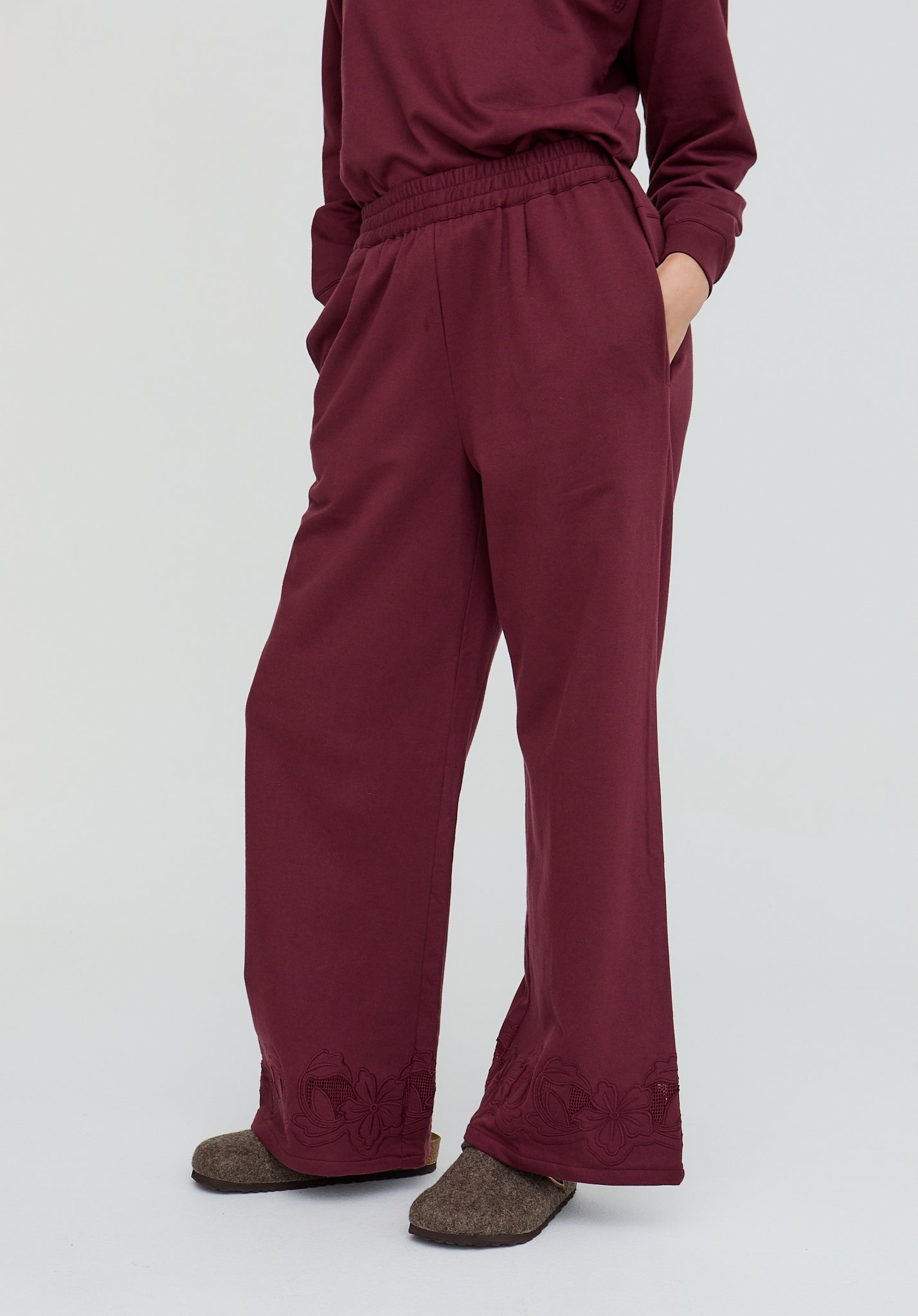 Maroon pants worn by a person on a white background