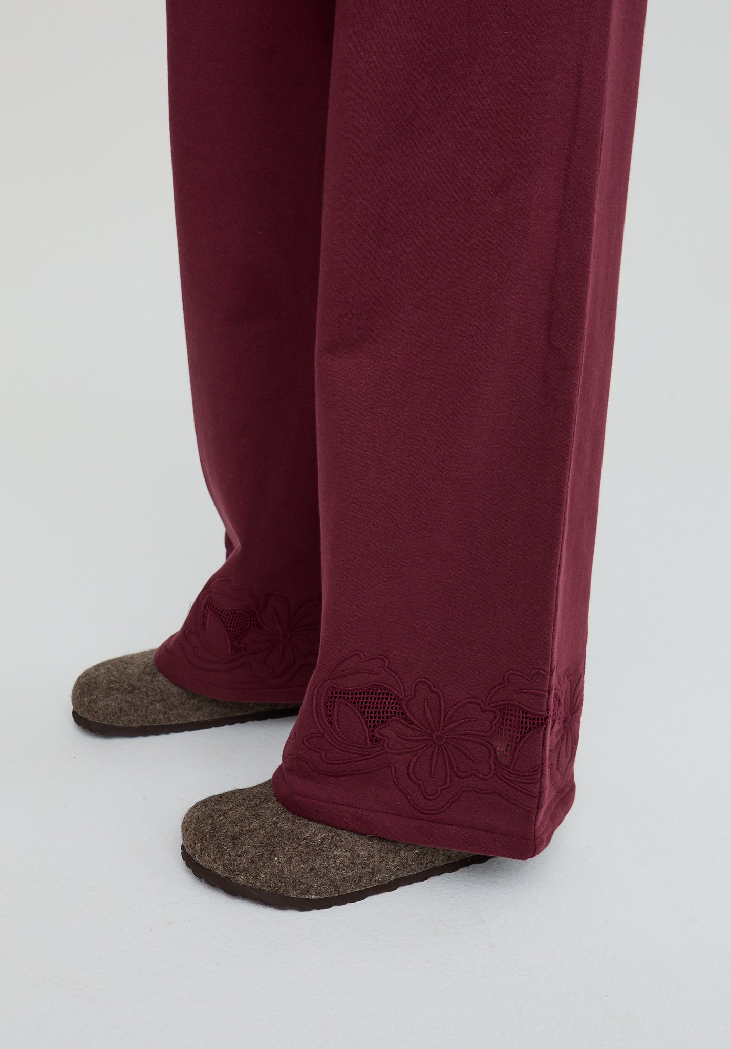 Maroon pants with brown slippers on a white background