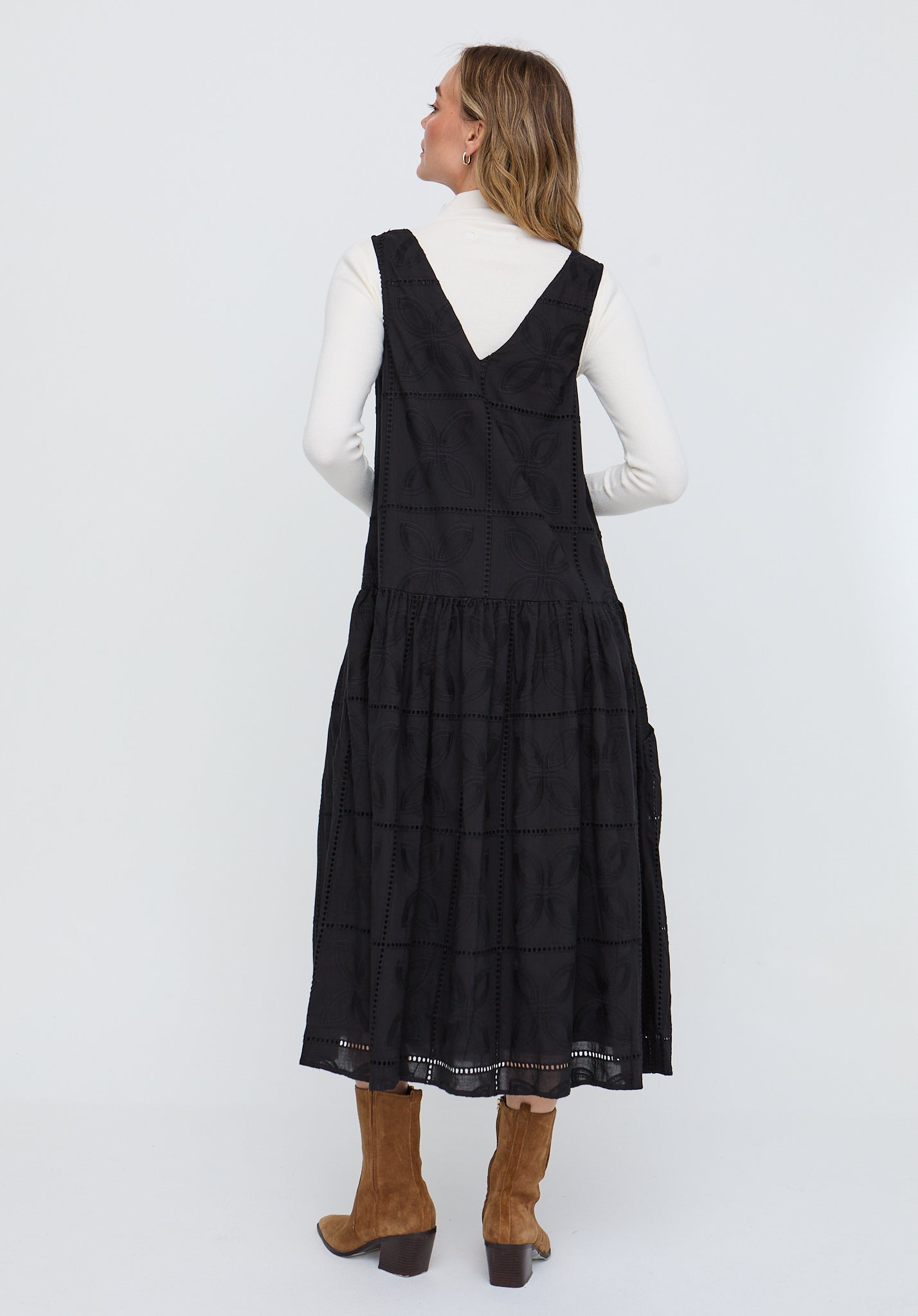 Woman wearing a black pinafore dress on a white background