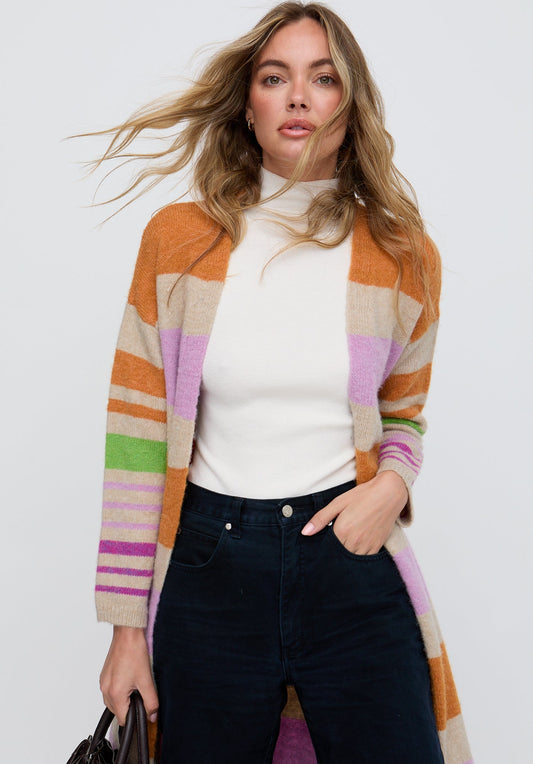 Woman wearing a colorful striped cardigan over a white top and dark jeans on a white background