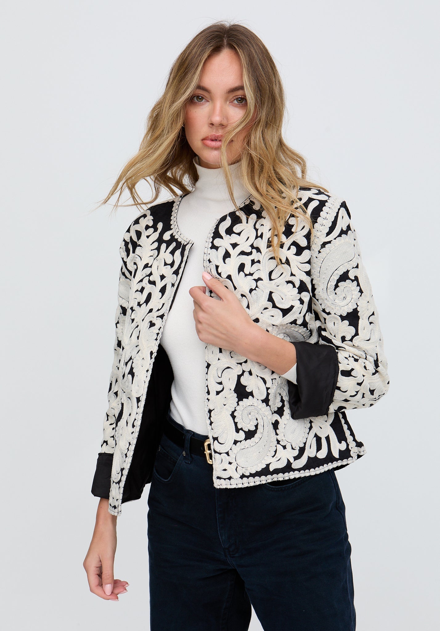 Woman wearing a black and white lace jacket on a white background