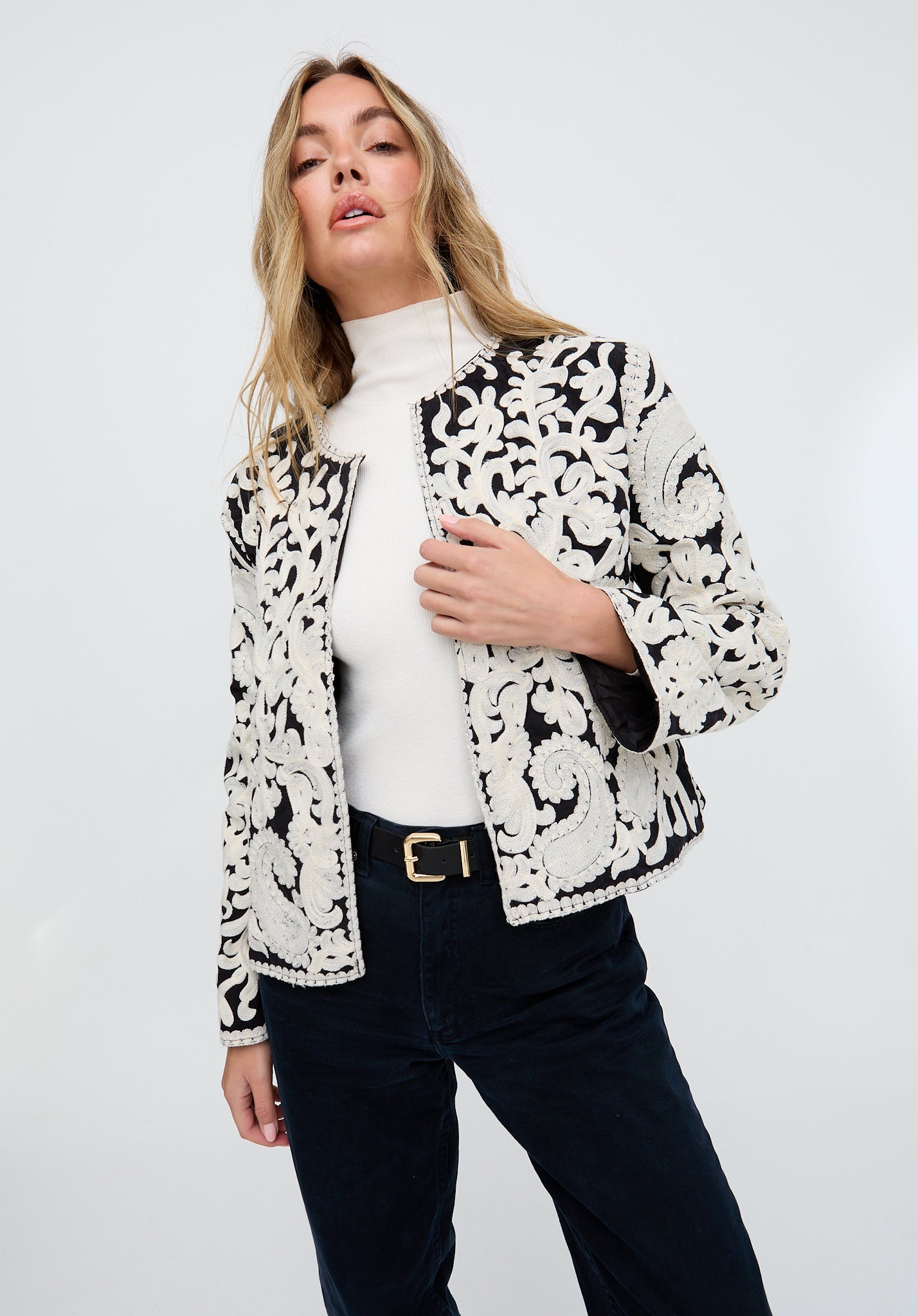 Woman wearing a black and white patterned jacket on a plain background