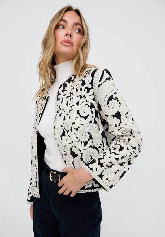 Woman wearing a black and white floral lace jacket on a white background
