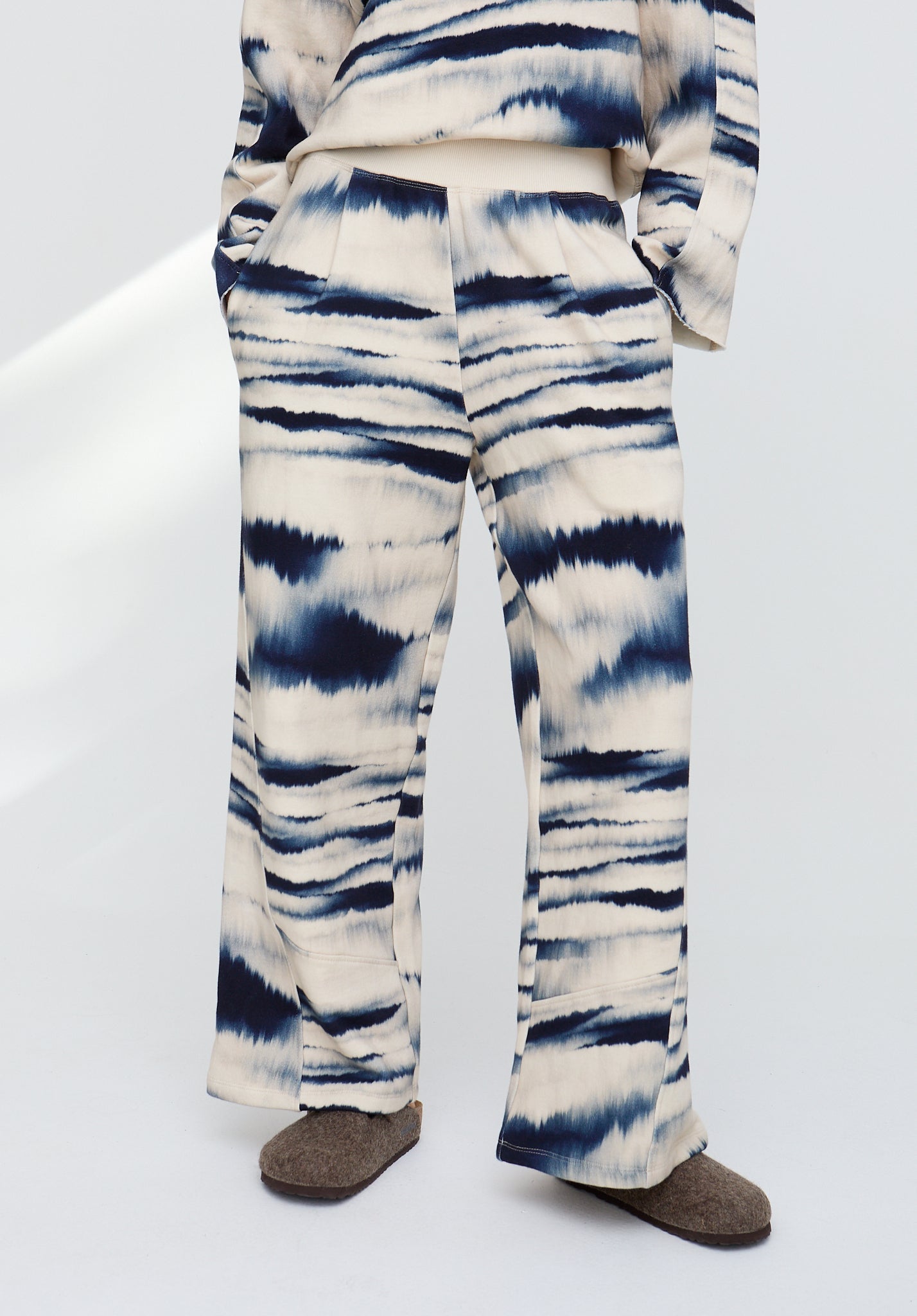 Tie-dye patterned pants worn by a person on a white background