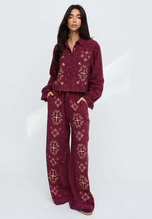 Woman wearing a burgundy patterned outfit on a white background