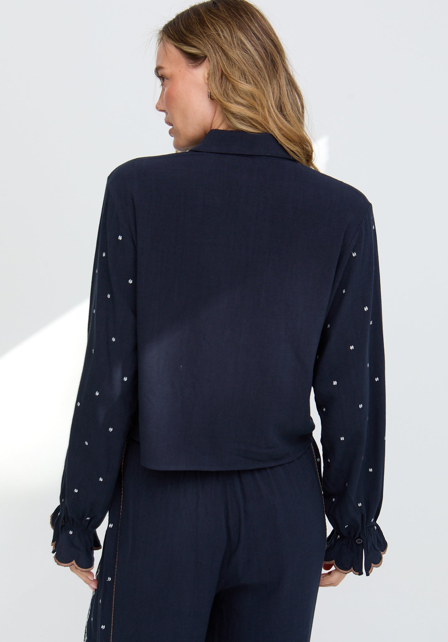 Navy blue blouse with white embellishments on a white background
