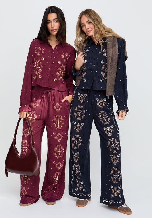 Two women wearing matching outfits with floral patterns on a white background