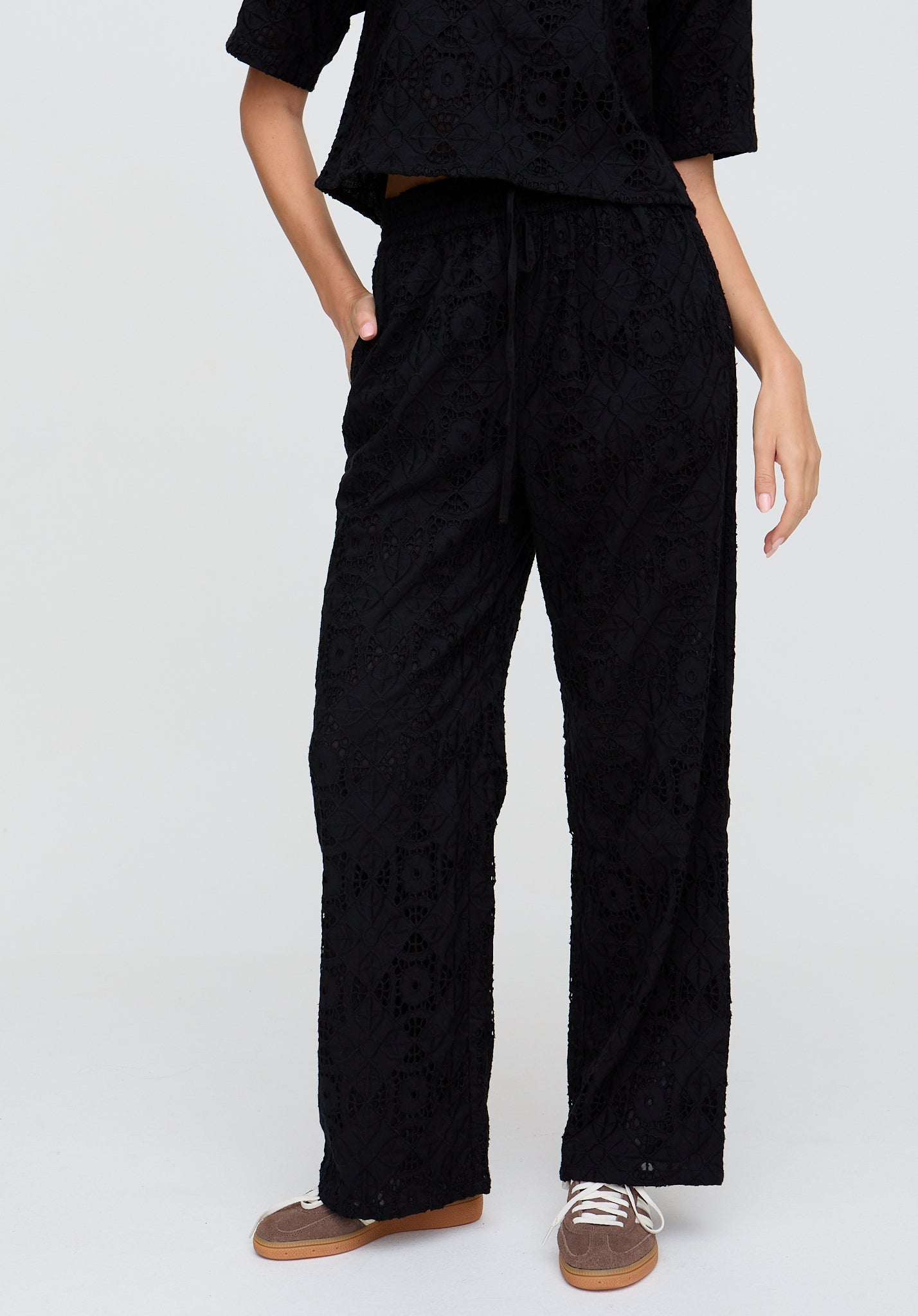 Person wearing black textured pants and top on a white background