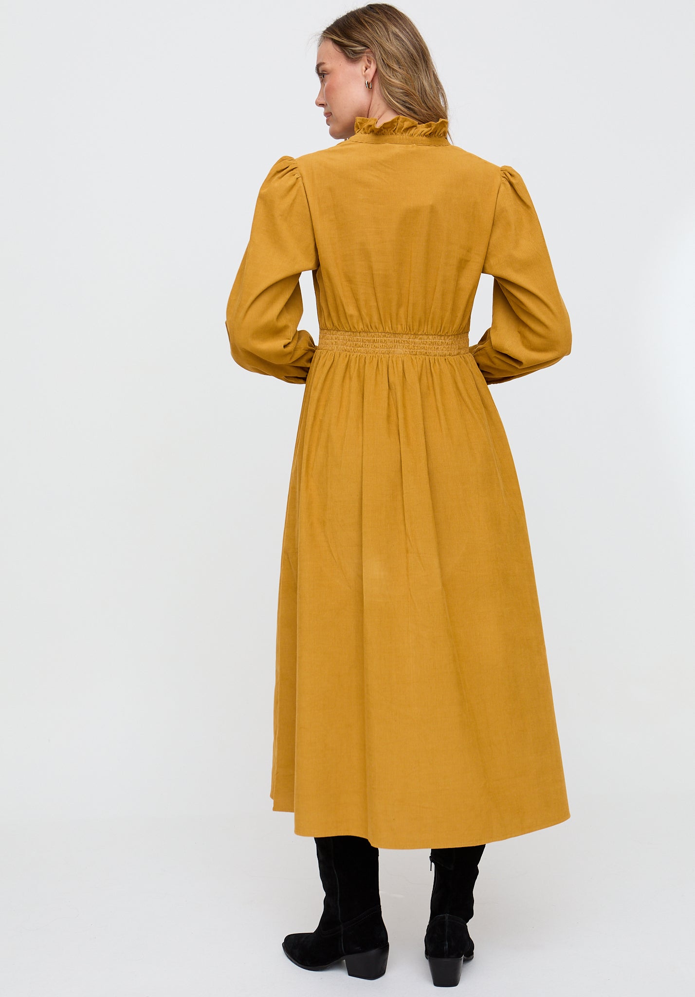 Woman wearing a mustard yellow dress on a white background