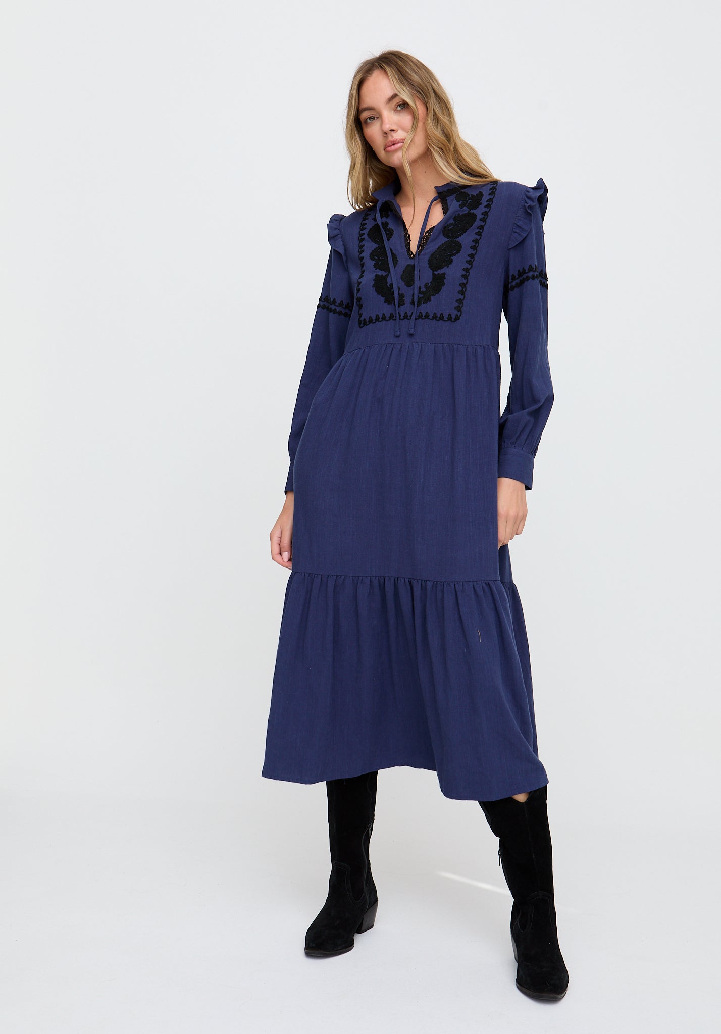 Woman wearing a blue dress with black embroidery on a white background