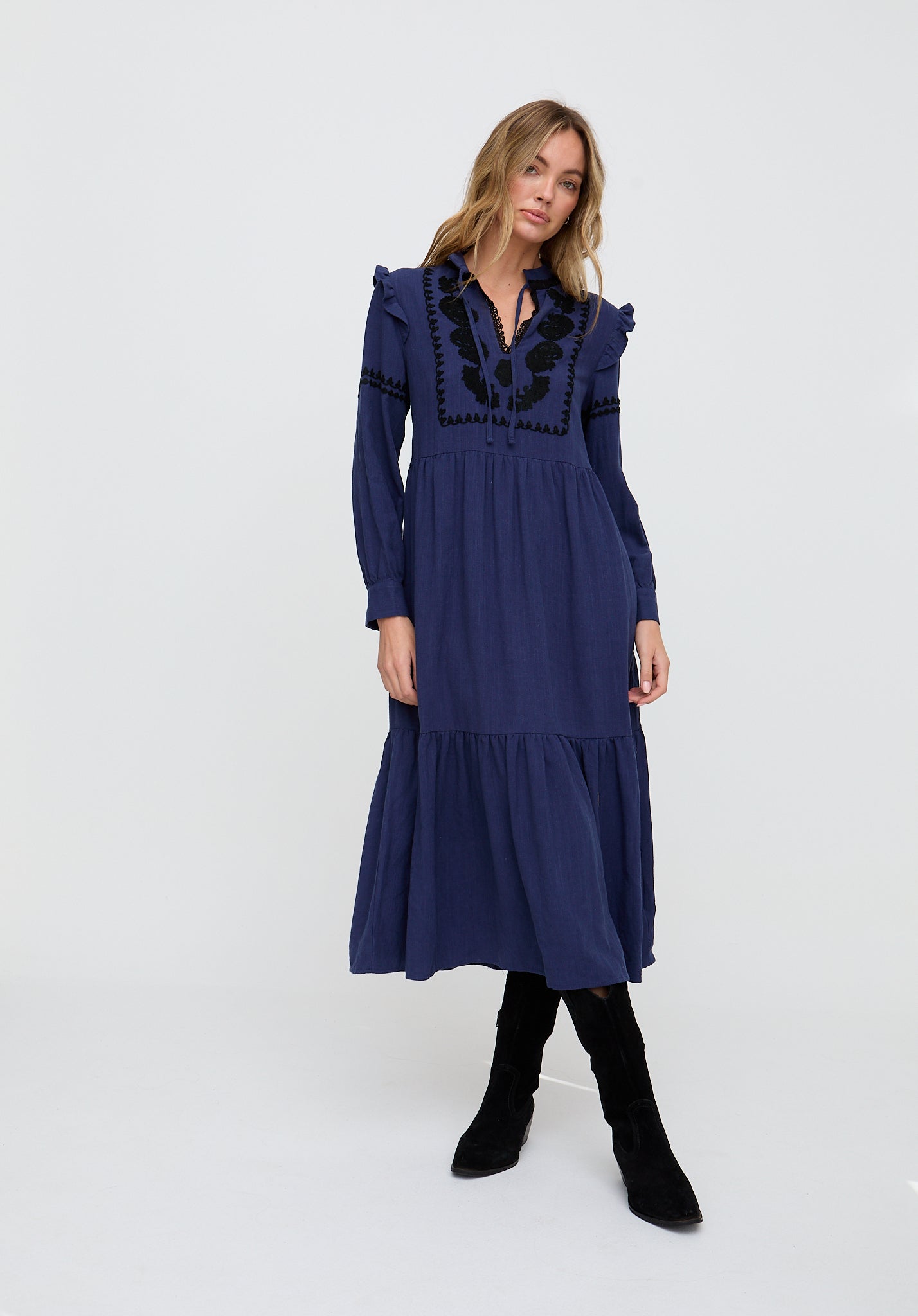 Woman wearing a blue dress with black embroidery on a white background