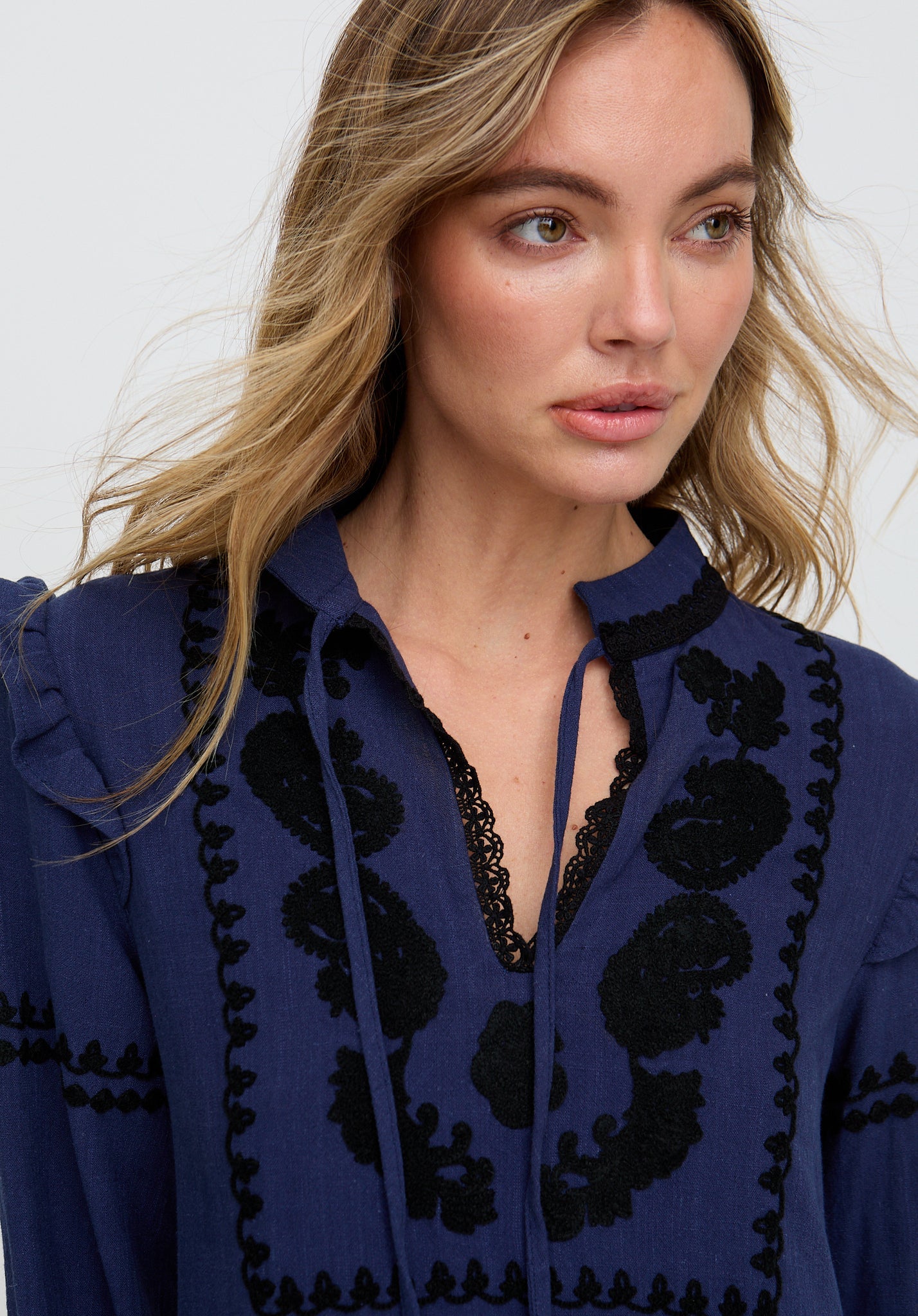 Woman wearing a blue blouse with black floral patterns on a white background