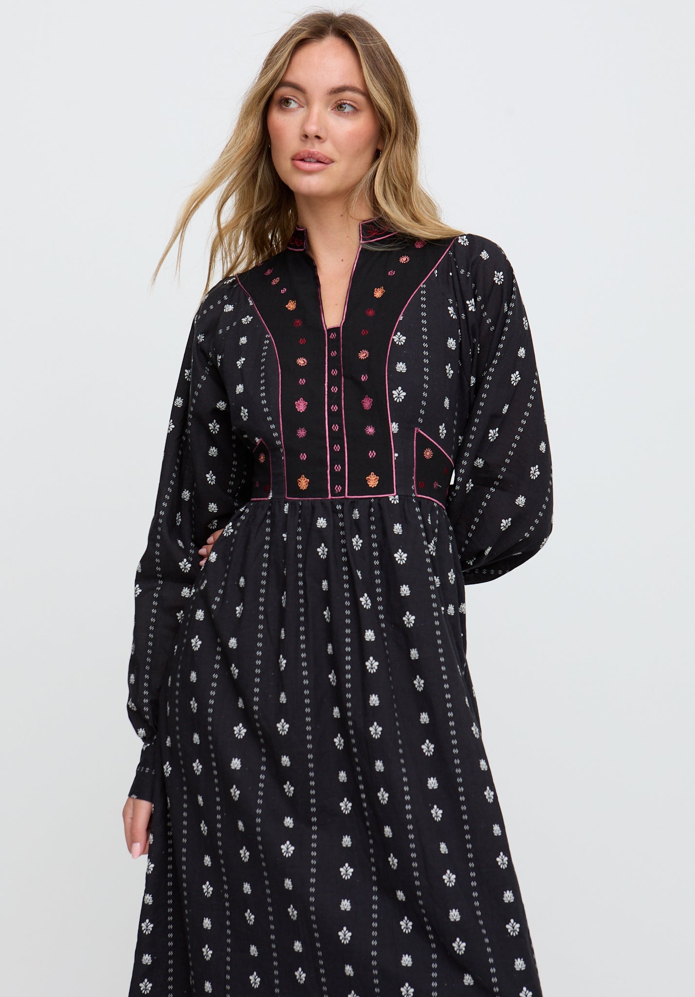 Woman wearing a black patterned dress on a light gray background