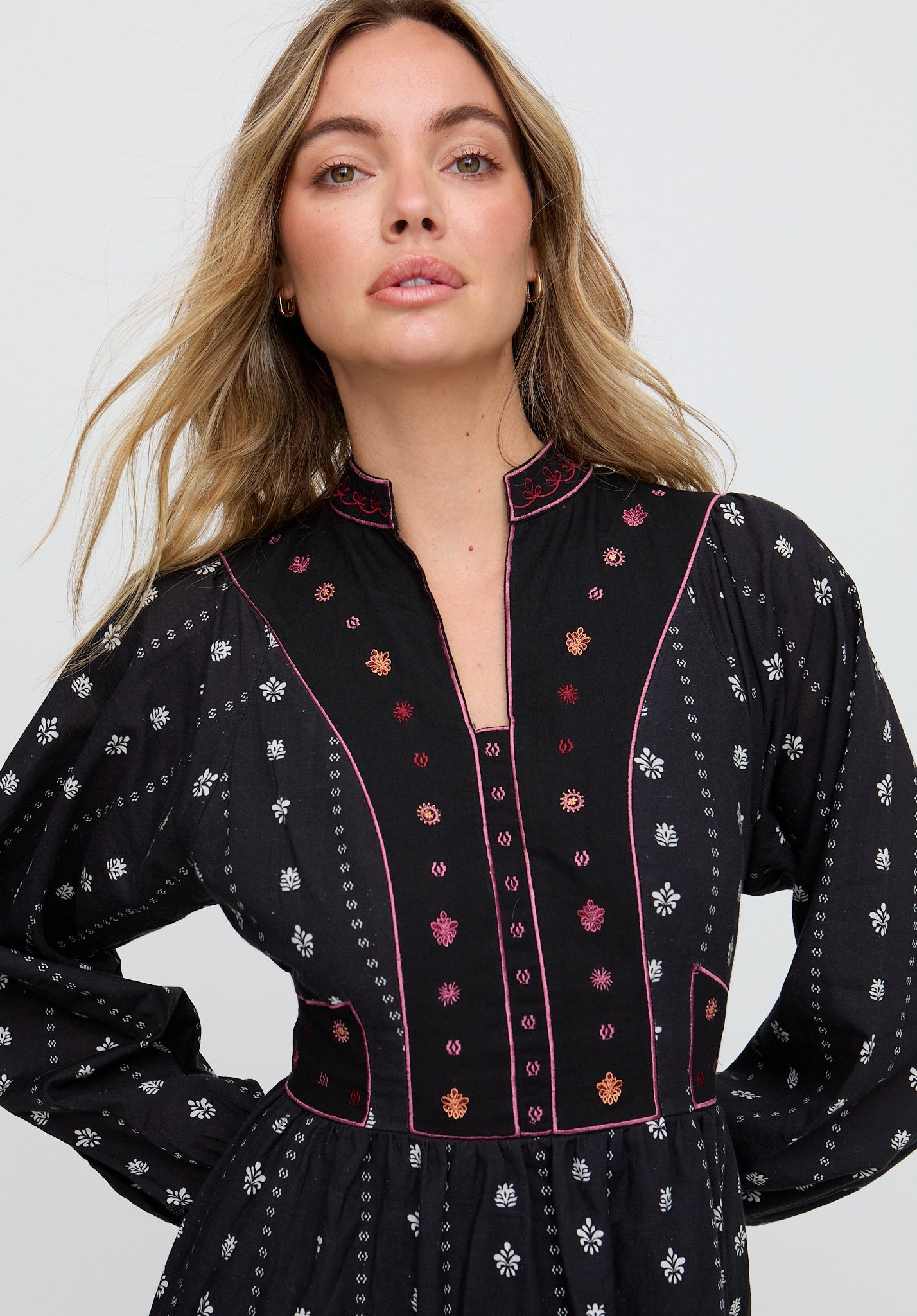 Woman wearing a black dress with floral embroidery on a white background