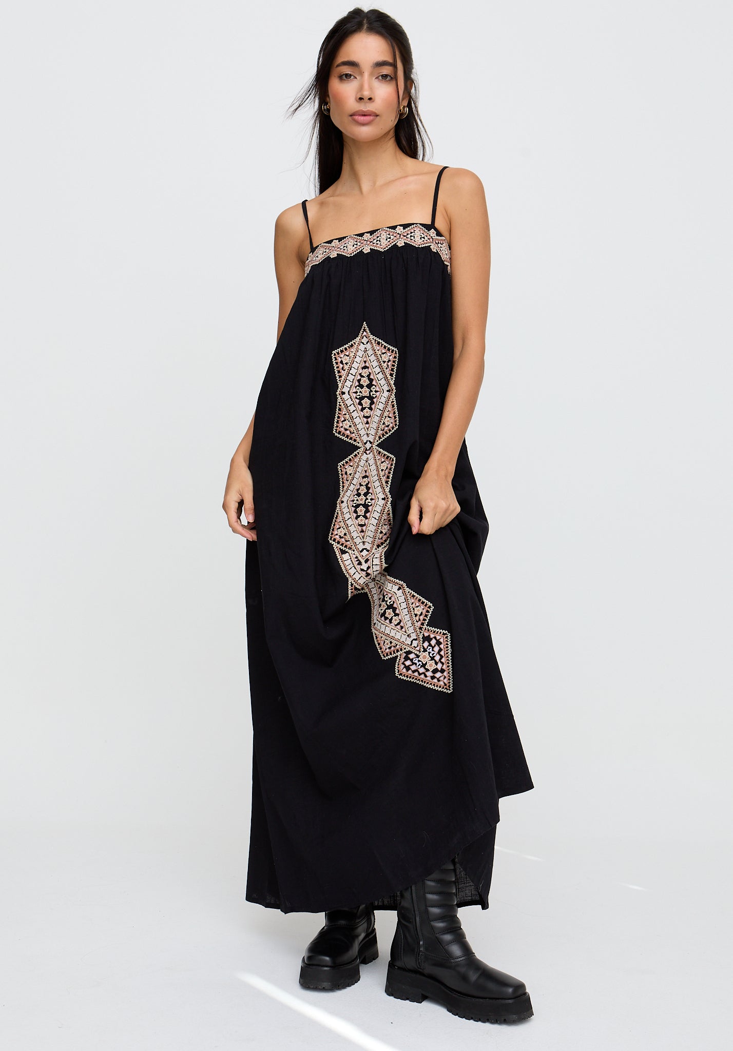 Woman wearing a black dress with intricate embroidery on a white background