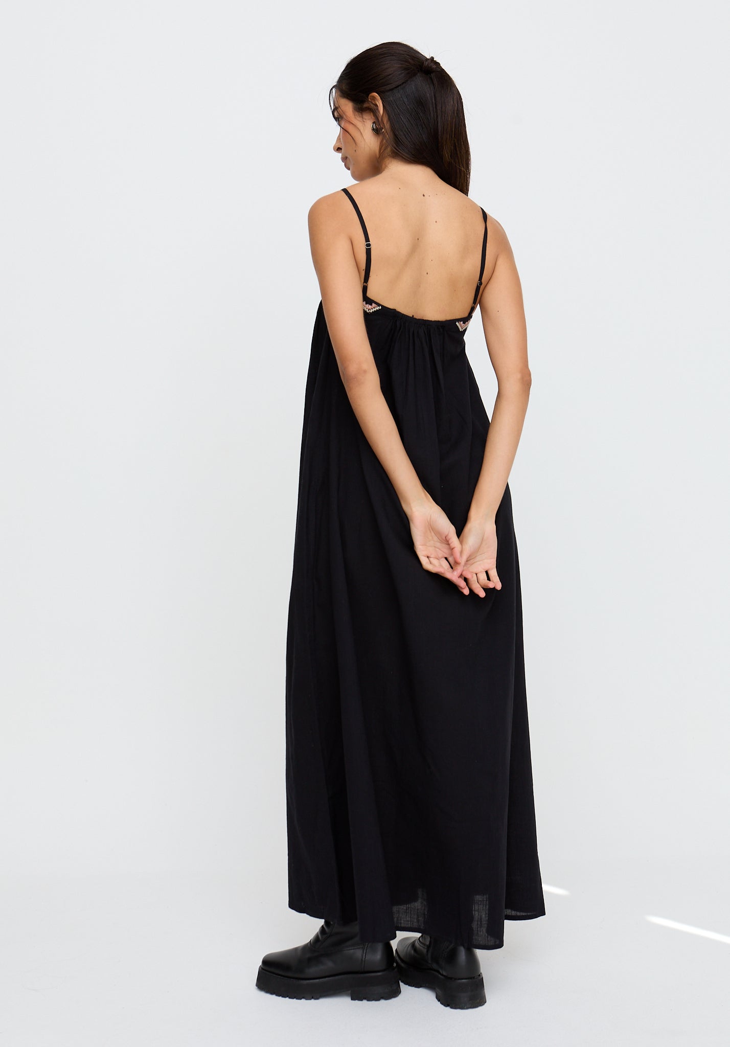 Woman wearing a black slip dress with thin straps on a white background