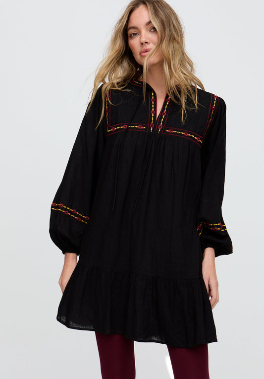 Woman wearing a black dress with red embroidery on a white background