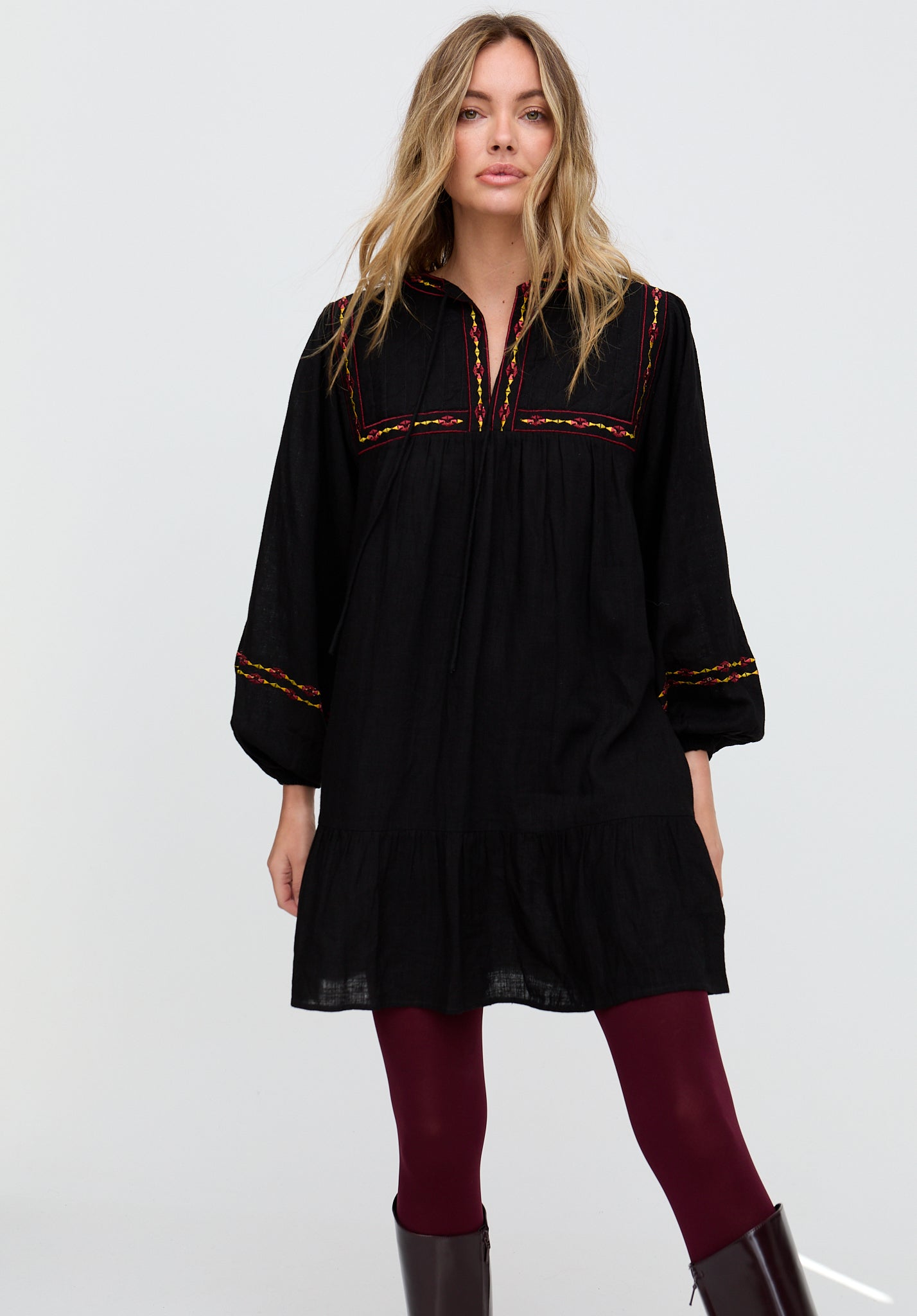 Woman wearing a black dress with red embroidery on a white background