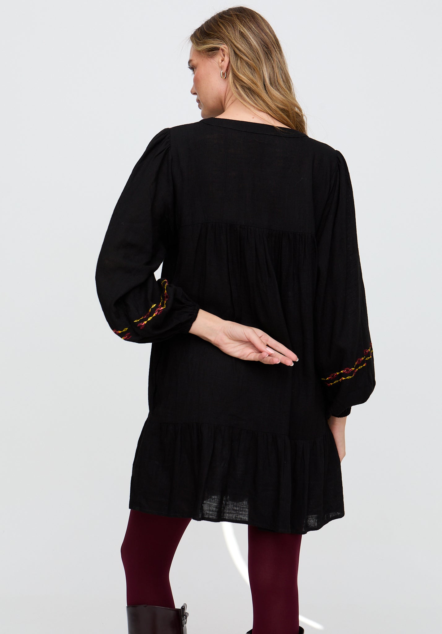 Woman wearing a black dress with long sleeves and red accents on a white background