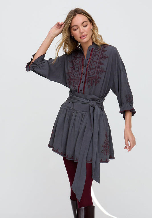 Woman wearing a gray dress with red embroidery on a white background