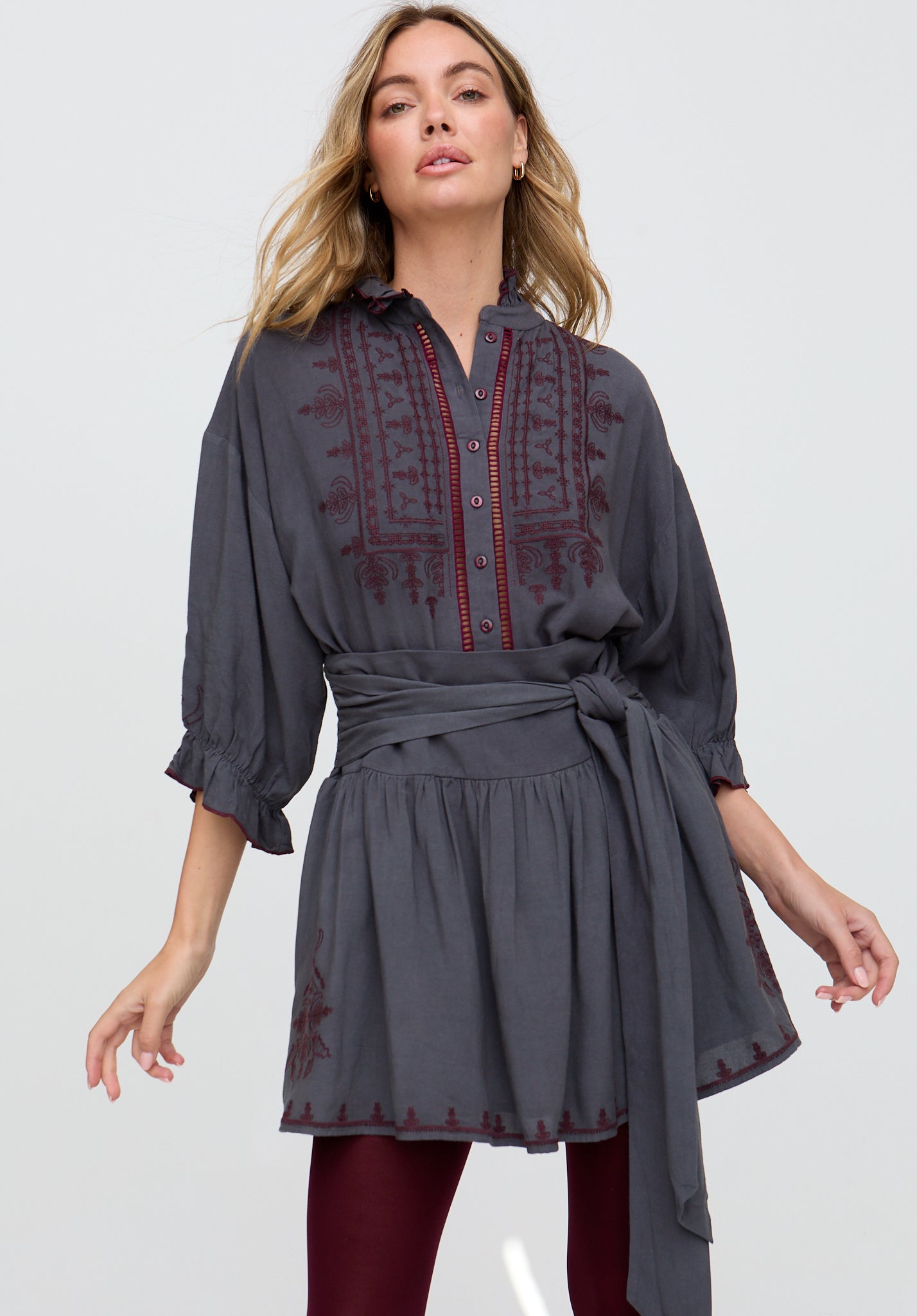 Woman wearing a gray dress with red embroidery on a white background