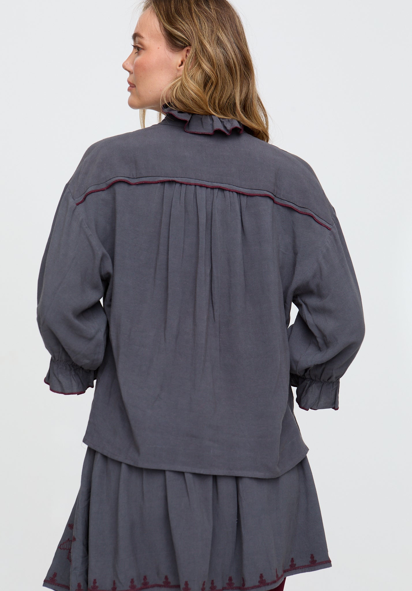 Woman wearing a gray outfit with red trim on a white background