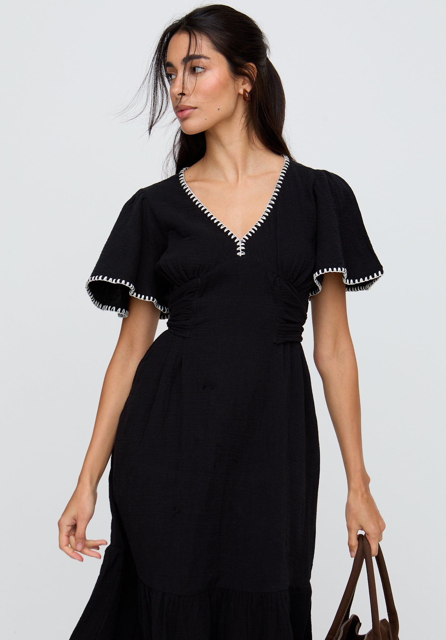 Woman wearing a black dress with white trim on a plain background