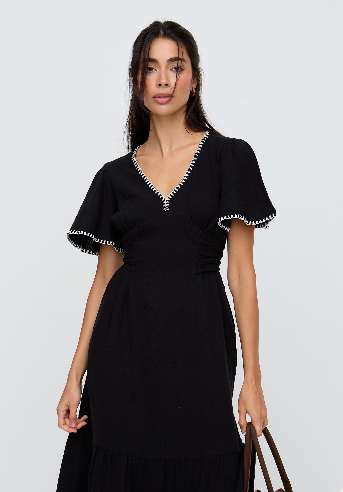 Woman wearing a black dress with white trim on a plain background