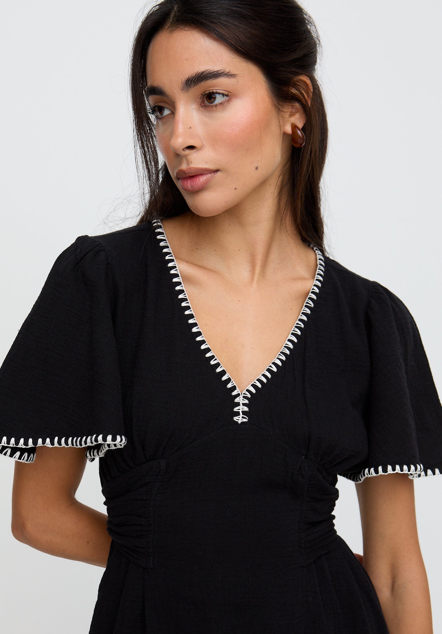 Woman wearing a black dress with white trim on a plain background