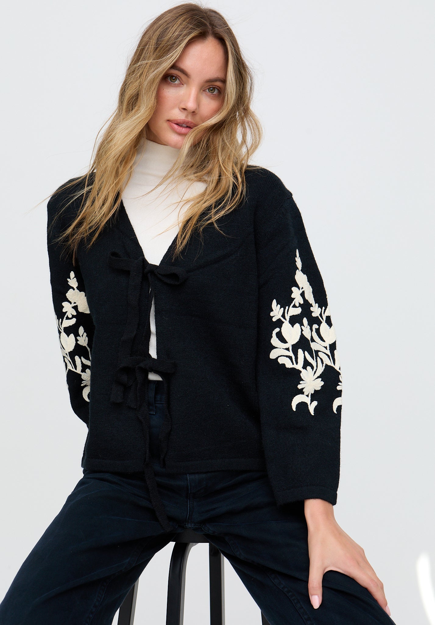 Woman wearing a black outfit with white floral patterns on a white background