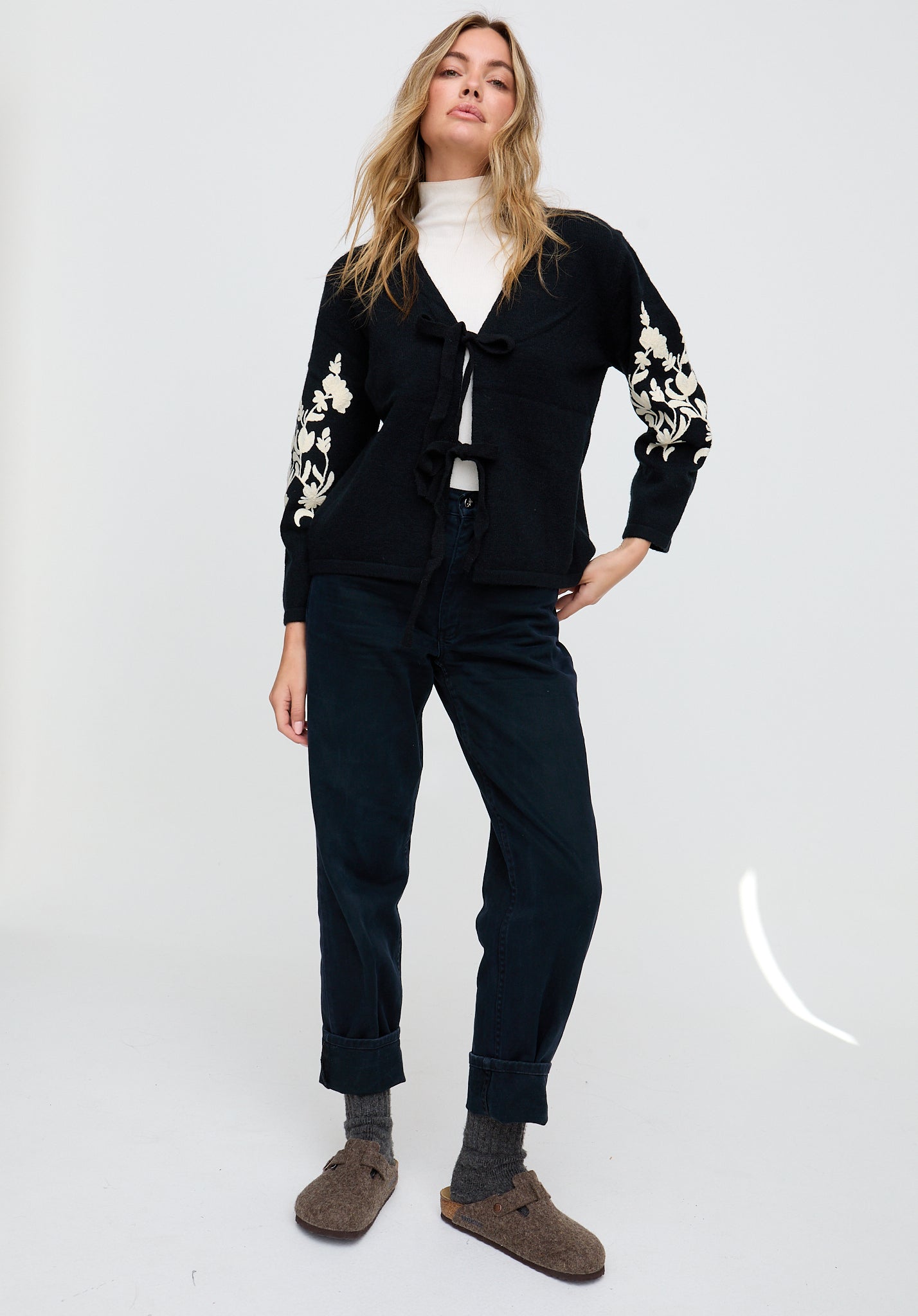 Woman wearing a black outfit with floral embroidery on a white background