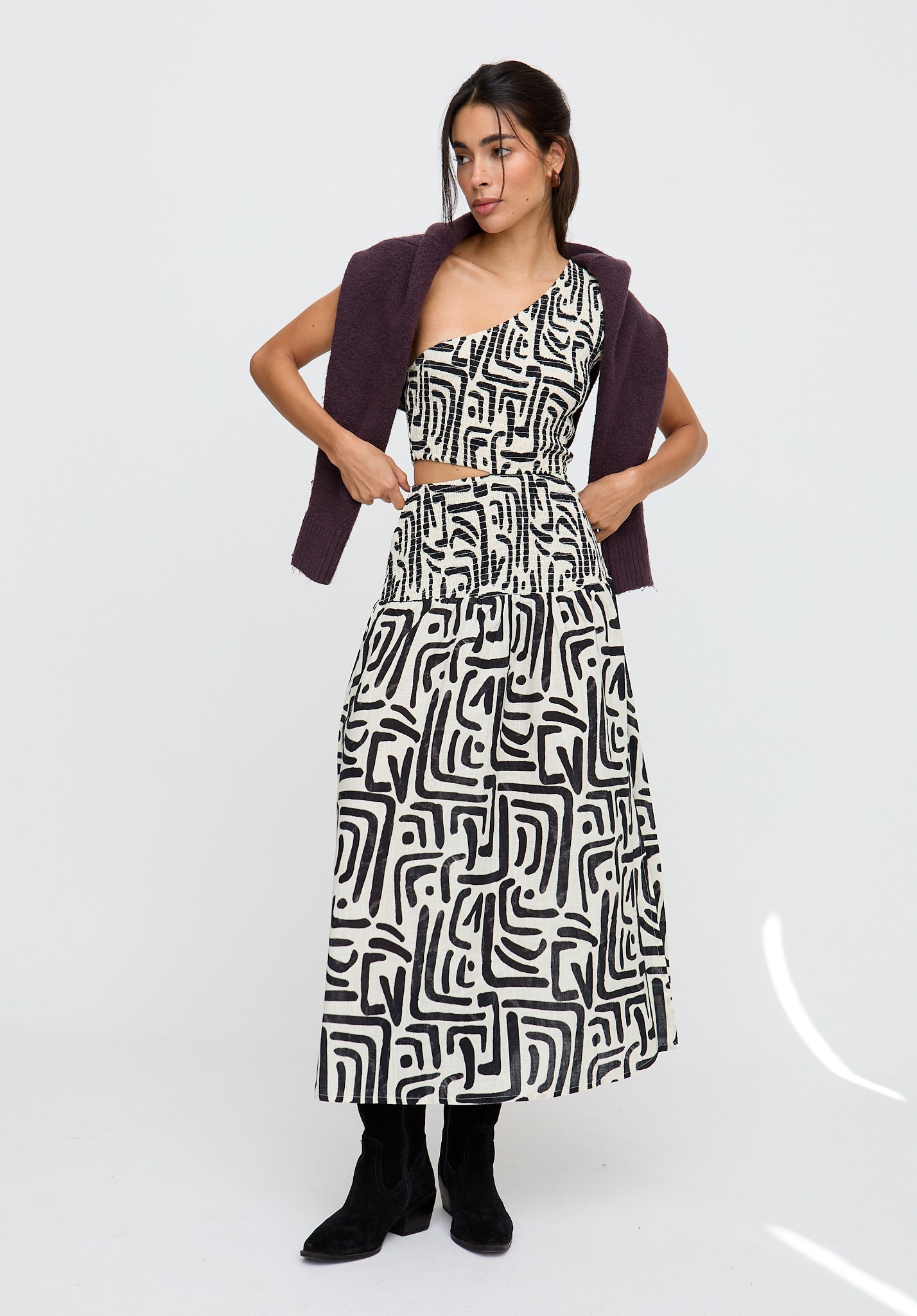 Woman wearing a patterned dress with a purple cardigan on a white background