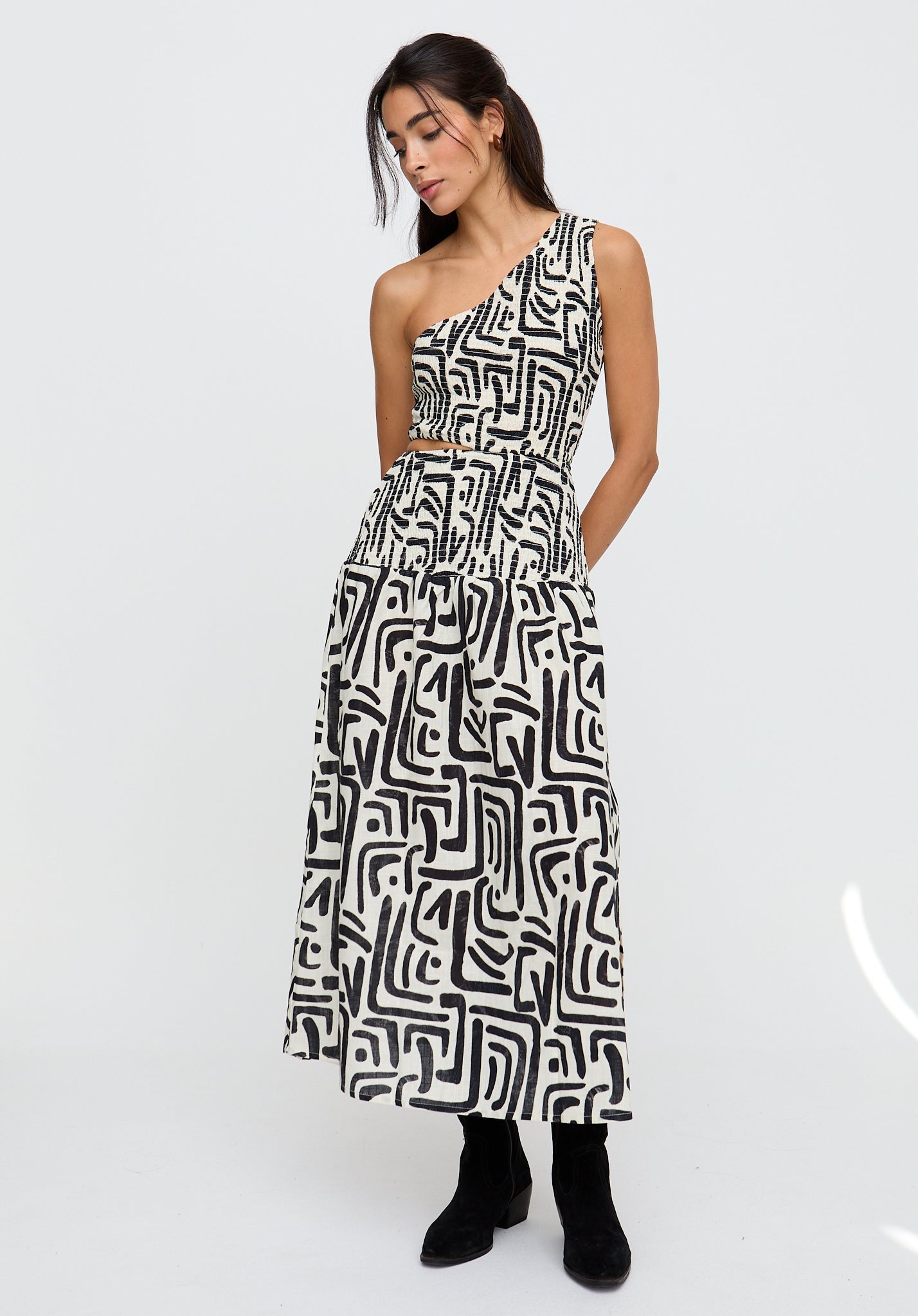 Woman wearing a black and white patterned one-shoulder dress on a white background