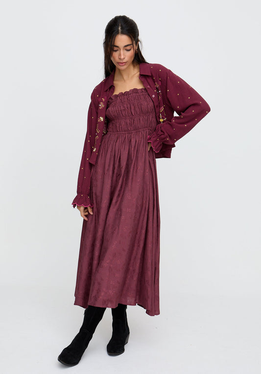 Woman wearing a burgundy dress with a matching jacket on a white background