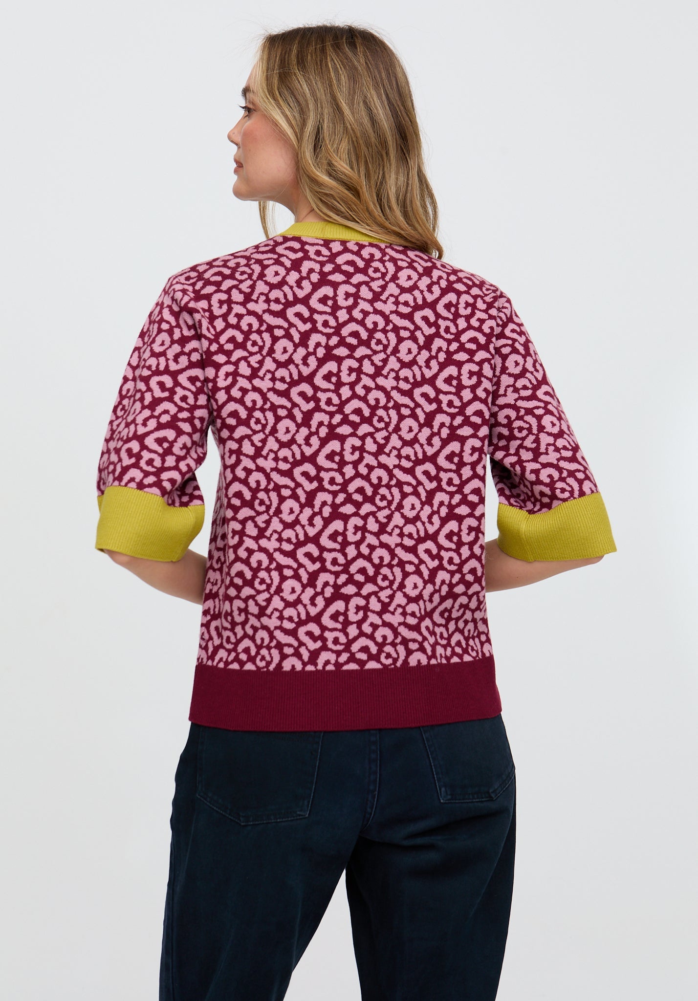 Woman wearing a pink patterned top with green sleeves on a white background