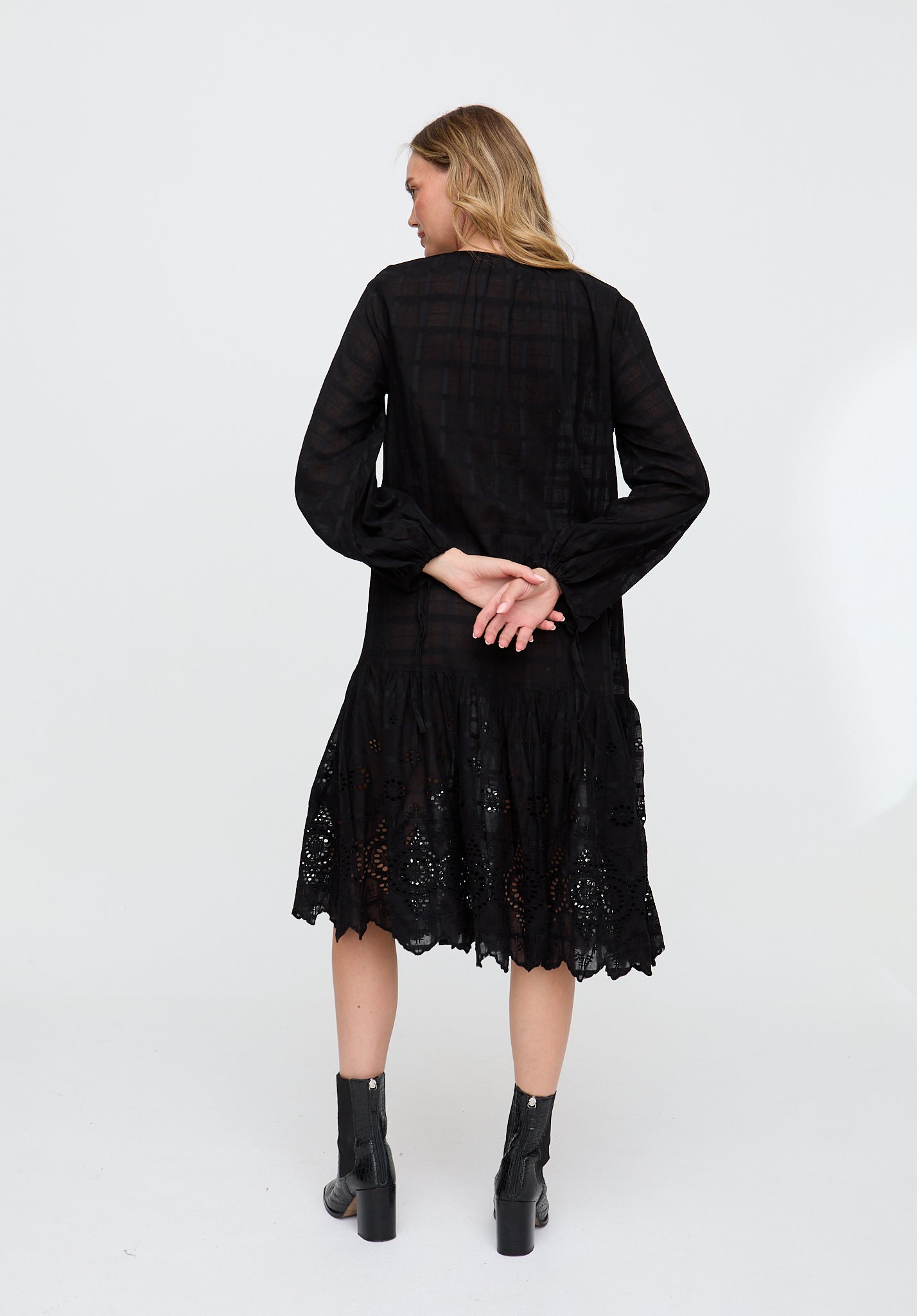 Woman wearing a black dress with lace details on a white background