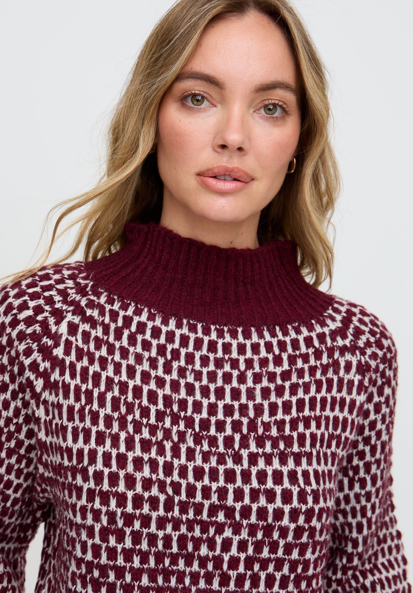 Woman wearing a patterned sweater against a plain background