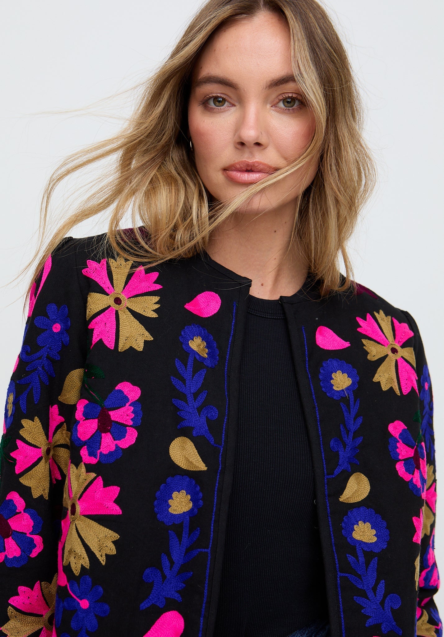 Woman wearing a black jacket with colorful floral patterns on a white background